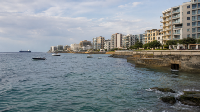 Ουδέτερη, φωτορεαλιστική editorial εικονογράφηση του παραλιακού μετώπου μιας σύγχρονης μεσογειακής πόλης, με Η εικόνα αποτελεί προϊόν Τεχνητής Νοημοσύνης.