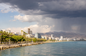 Ηλιόλουστη ακτή της Λεμεσού με καταιγίδα να αναπτύσσεται πάνω από τα ορεινά