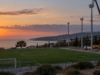 Συμβολική απεικόνιση ποδοσφαιρικού γηπέδου και φωτιστικών ιστών σε παραθαλάσσια περιοχή