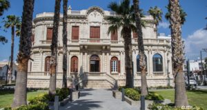 Η Δημοτική Πανεπιστημιακή Βιβλιοθήκη Λεμεσού με την ιστορική πρόσοψη και τους φοίνικες